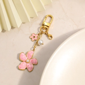 Close-up of golden keychain with pink enamel flower pendant and elegant pearl accents