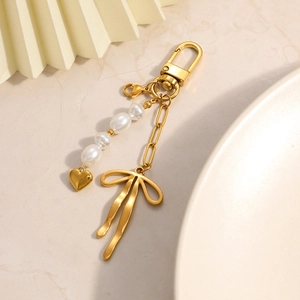Elegant gold bow and pearl heart keychain detail with polished metal lobster clasp