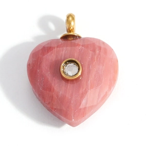 Dettaglio macro del ciondolo a cuore in pietra rosa con bordo dorato e cristallo