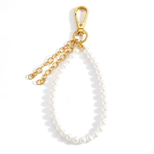 Close-up of pearl bead ring with golden clasp and decorative hanging metal chains