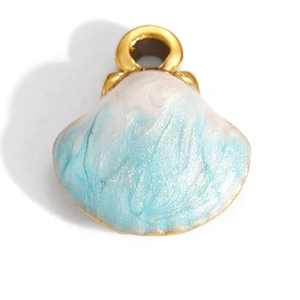 Detail view of a shell pendant with blue enamel marbling and gold plated metal edges