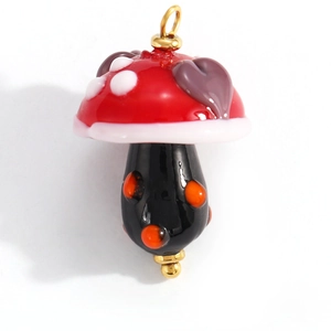 Detailed view of colorful glass mushroom pendant with red cap and gold metal loops