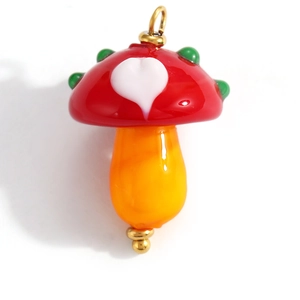 Detail of red mushroom pendant with heart pattern and gold metal connectors