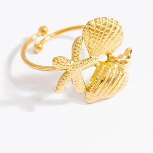 Dettaglio di ornamenti dorati a forma di stella marina e conchiglia su bracciale rigido