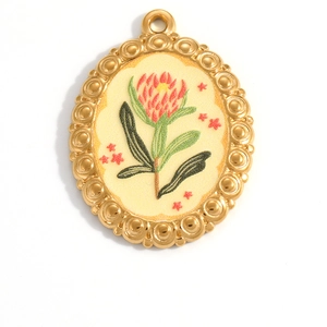 Macro shot of oval gold-plated pendant with vintage floral pattern and star details