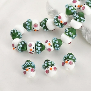 Detailed view of handmade snowman glass beads with green Christmas hats for DIY jewelry making