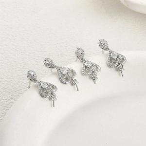 Macro view of four silver-plated lace heart ear studs with cubic zirconia and pearl pegs