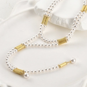 Detail of 14k gold-plated textured metal spacer beads and pearls on layered necklace