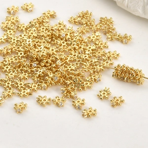 Detailed close-up of 4mm gold plated snowflake spacers with cubic zirconia for DIY jewelry