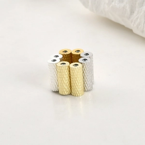 Close-up of 14k gold and silver magnetic cylinder beads with diamond-cut texture for DIY jewelry