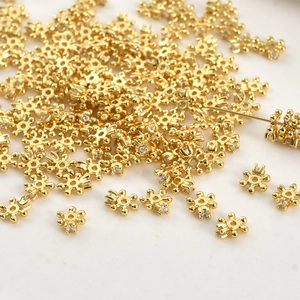 Close-up of gold-plated snowflake spacer beads with zircon for DIY jewelry making