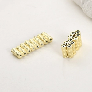 Macro detail of 14k gold plated cylindrical beads with textured knurled diamond patterns