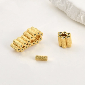Detailed view of 14k gold-plated cylindrical beads with cross-knurled texture for DIY jewelry