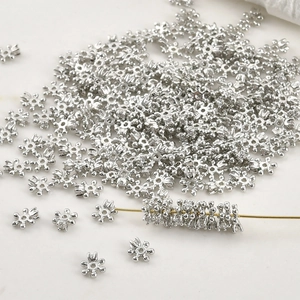 Close-up of 4mm silver snowflake spacer beads for DIY jewelry making and bead threading