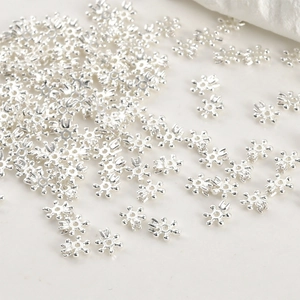 Macro shot of silver hexagonal snowflake spacer beads for DIY jewelry making and crafting