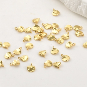 Vista macro de dijes de hojas bañados en oro de 14k con textura martillada artesanal