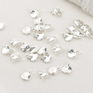 Detalle de colgantes de hojas plateadas irregulares con anillas para crear joyas DIY