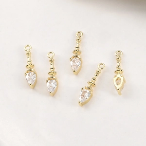Close-up of five gold-plated pendant charms with teardrop zircon crystals for DIY jewelry