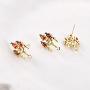 Macro detail of 14k gold plated earring studs with three red pear-cut zircon stones