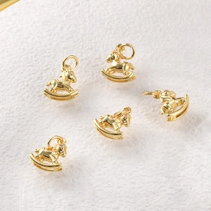 Detailed view of five gold-plated rocking horse charms with zirconia eyes for DIY jewelry