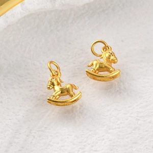 Macro detail of two matte gold rocking horse pendants with fine sand finish texture