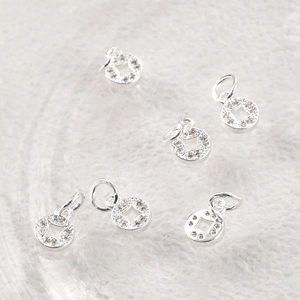 Macro view of silver-tone ancient coin pendants with white zircon inlays for DIY jewelry