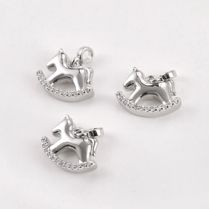 Vue macro de trois breloques cheval à bascule plaquées argent avec détails en zircone