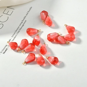 Macro detail of translucent pomegranate seed resin charms with gold metal rings