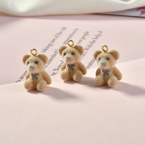 Detailed view of plush bear charms with flocking texture and gold metal hooks