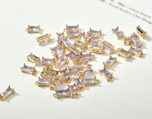 Macro view of purple rectangular crystal charms with 18k gold plated double rings