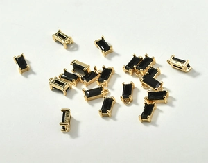 Detailed macro view of 18k gold-plated rectangular pendants with black crystal glass stones