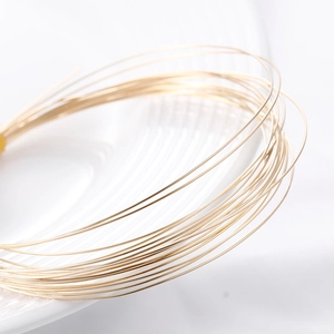 Polished 14k gold-filled craft wire for DIY jewelry making on a white ceramic tray