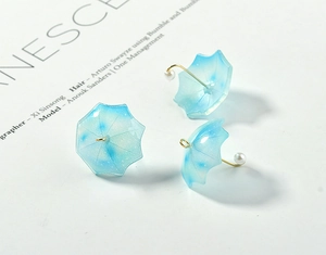 Detailed view of blue gradient umbrella charms with gold accents and pearl for jewelry DIY