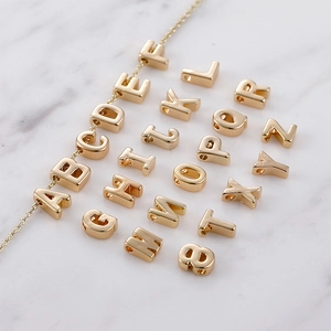 Makro-Detail von 14k goldgefüllten 3D-Buchstabenanhängern an einer feinen Goldkette