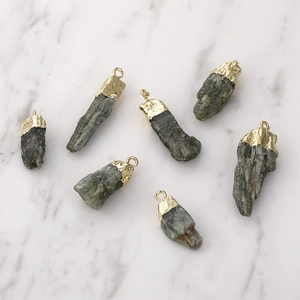 Colgante de cristal verde natural con baño de oro sobre fondo de mármol