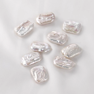 Irregular baroque freshwater pearl beads with iridescent luster on white silk background