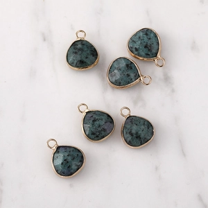 Close-up of five faceted dark green teardrop stone pendants with gold metal edging