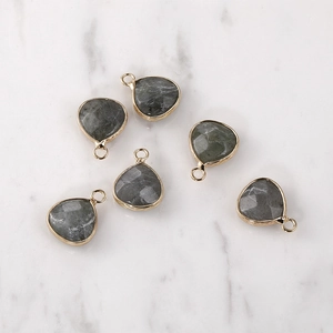Detailed view of faceted heart-shaped grey natural stone pendants with gold metal edges