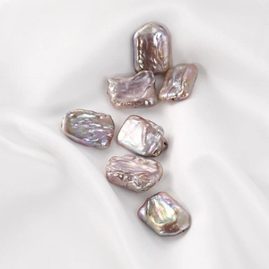 Close-up of iridescent pink baroque pearls on white silk for DIY jewelry making