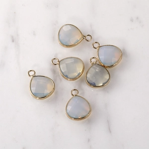Detail of six white faceted teardrop crystal charms with gold plating for jewelry DIY