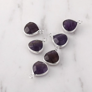 Detailed view of five faceted purple teardrop pendants with silver-edged metal frames