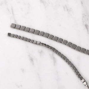 Close-up of polished gunmetal gray square hematite beads for DIY jewelry making