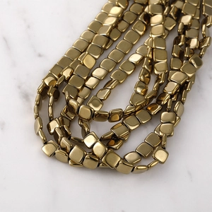 Polished gold square spacer beads for DIY jewelry making displayed on marble surface