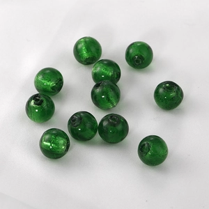 Macro shot of 11 dark green round lampwork glass beads with internal foil texture