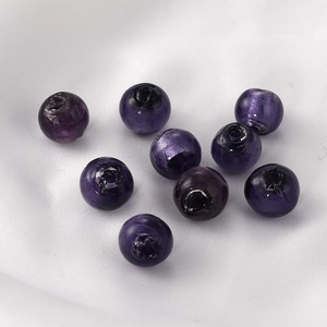 Macro view of purple glass beads with silver foil interior on white silk fabric