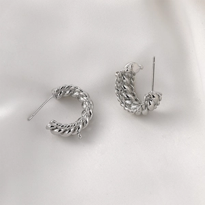 Vista macro de pendientes de aro en C plateados trenzados con textura de espiral