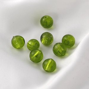 Macro shot of 8 translucent green glass beads with natural swirl textures on white silk