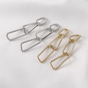 Detail view of 14k gold plated twisted rectangular link chain earrings on silk