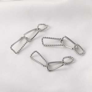 Detail of silver twisted rectangle links for DIY jewelry making on white fabric