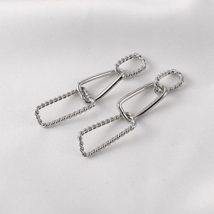 Silver geometric link chain earrings on white silk fabric with textured details